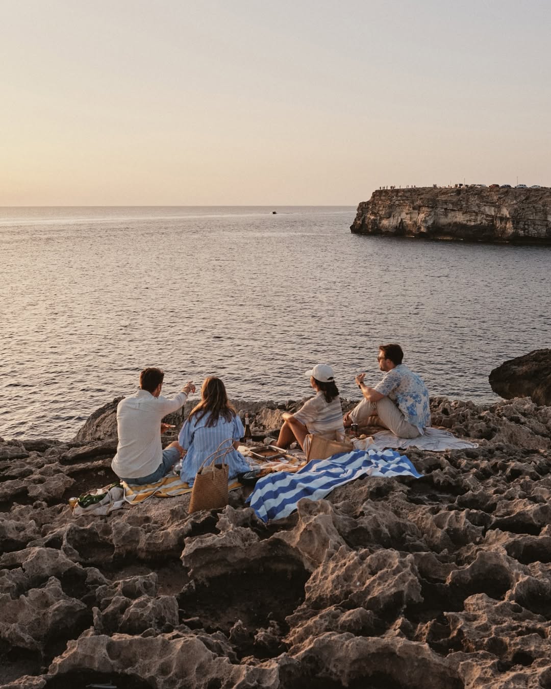 Grupo disfrutando de un picnic al atardecer en la costa de Menorca